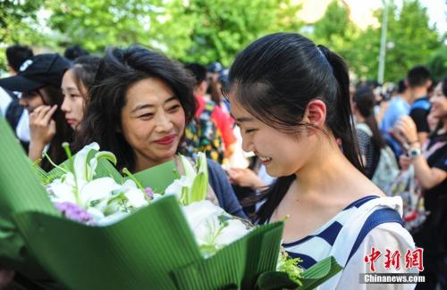 資料圖：山東濟(jì)南眾多考生手捧鮮花在家長的簇?fù)硐職g快告別高考。中新社記者 張勇 攝