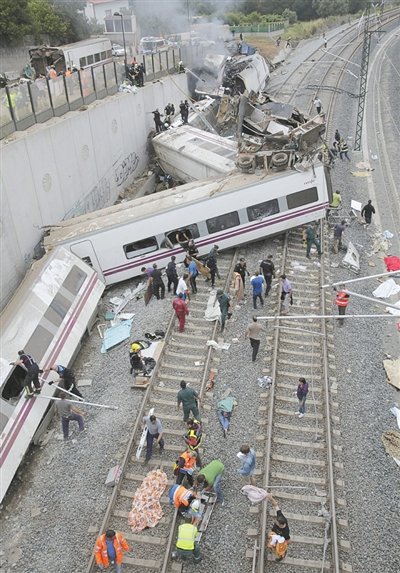 24日，救援人員在西班牙列車脫軌現(xiàn)場。一節(jié)車廂被強(qiáng)大的慣性拋上鐵道邊的高臺。