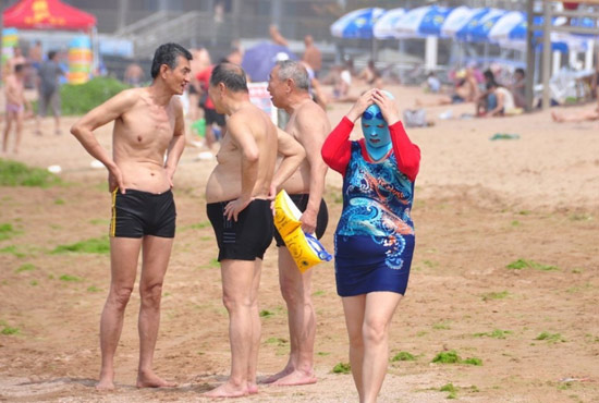 2013年7月3日，山東青島青島高溫來襲，“青島大媽”不懼滸苔，戴著“強盜面具”出現(xiàn)在海水浴場消暑降