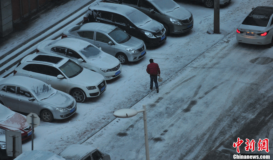 11月18日，行人在沈陽街頭的積雪中穿行。