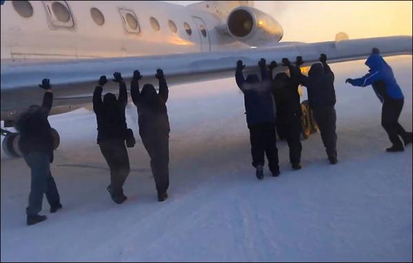 伊加爾市一架客機起飛前被凍在了跑道上。飛機上的乘客不得不下來推飛機。