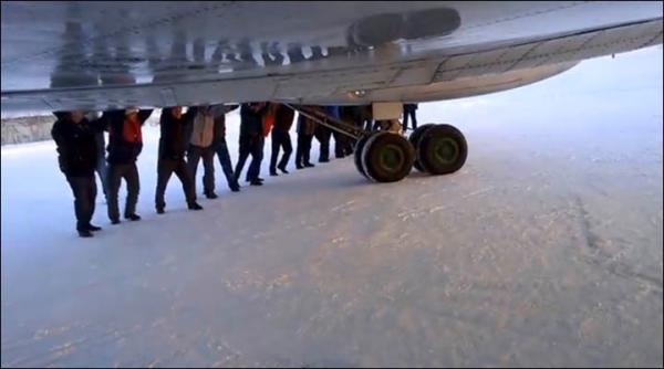 　伊加爾市一架客機起飛前被凍在了跑道上。飛機上的乘客不得不下來推飛機。