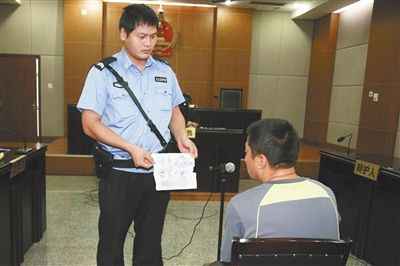 昨日庭審中，法警向趙某出示其扎完車胎后所留辱罵公司的紙條。通訊員 李秀文 攝
