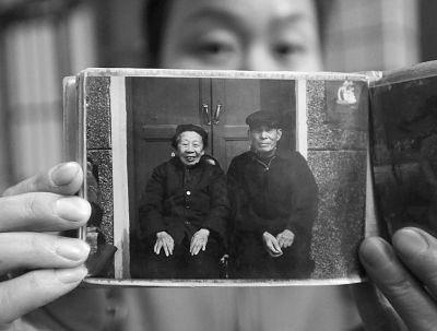 圖為孫女拿出兩位老人上世紀(jì)80年代在家門口的合影給記者看。記者楊濤 攝