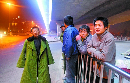 冬夜里，農(nóng)民工在橋下等著干活兒。