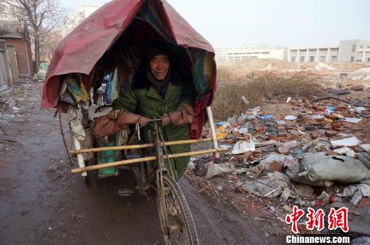 圖為老人走出窩棚，推著三輪車準備出去撿拾廢品。周小云 攝