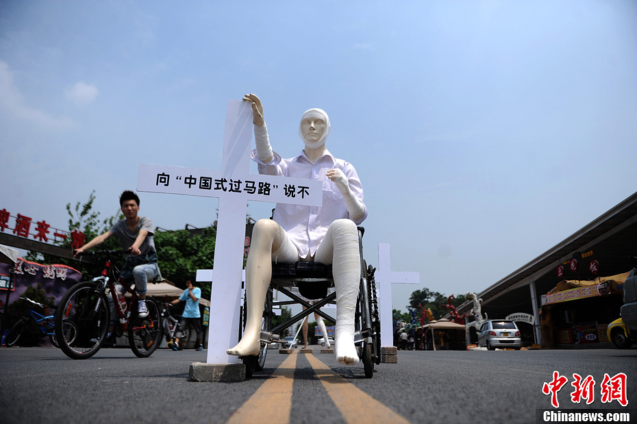 4月16日，重慶市洋人街上擺放著兩個(gè)受了傷的塑料人像“模特”，旁邊十字架上寫著向“中國式過馬路”說不