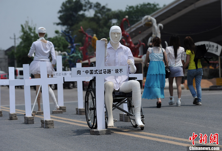 4月16日，重慶市洋人街上擺放著兩個(gè)受了傷的塑料人像“模特”，旁邊十字架上寫著向“中國式過馬路”說不