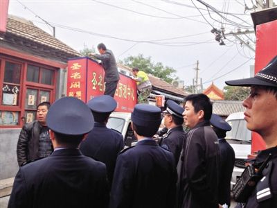 昨日下午,東城區(qū)工商、城管、公安等部門,對(duì)雍和宮附近的預(yù)測(cè)中心進(jìn)行清理整頓,站在車頂?shù)膬擅と苏鸪患摇邦A(yù)測(cè)中心”的招牌。因雍和宮、白云觀等文化景點(diǎn)外聚集大量算命先生,被媒體稱為“算命一條街”。本版攝影/新京報(bào)記者 李寧 攝