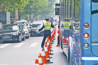 省人民醫(yī)院南門的路中間擺放反光錐，交警示意由西向東車輛從前方繞行。