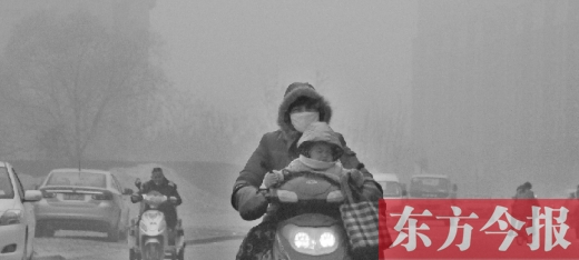 12月8日，鄭州市未來路上，一位市民帶著孩子在霧中騎行