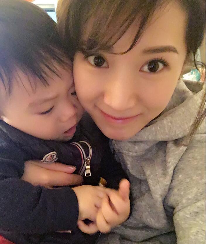 照片中李念狂吻兒子，小寶貝自顧自地玩著。