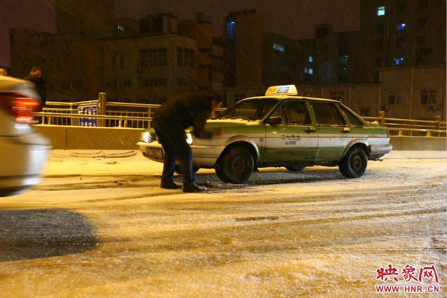 一位出租車司機(jī)在車輪前灑上雪，希望能增加輪胎的摩擦力。