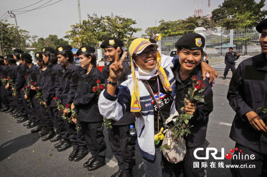 2013年12月03日,曼谷總理府與曼谷警署允許反政府示威民眾進入,雙方進入暫時“停戰(zhàn)”狀態(tài)迎接泰王生日。曼谷警察總署,女警們手持鮮花送給反政府示威民眾。圖片來源:Manish Swarup/東方IC