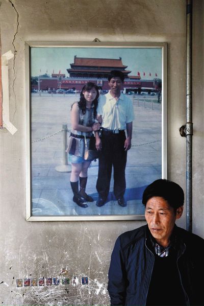 11月14日，承德市平泉縣，潘小梅父母的家，潘小梅父親靠在墻上，身后掛著數(shù)年前他和潘小梅在北京的合影照片。新京報記者