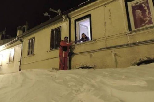 一個居民站在積雪上，可以與一名二樓鄰居在窗口握手。（來源：意大利氣象局）