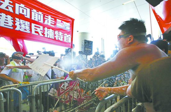 17日，在香港立法會(huì)外，一名反對(duì)政改的男子向支持派人群投擲標(biāo)牌。