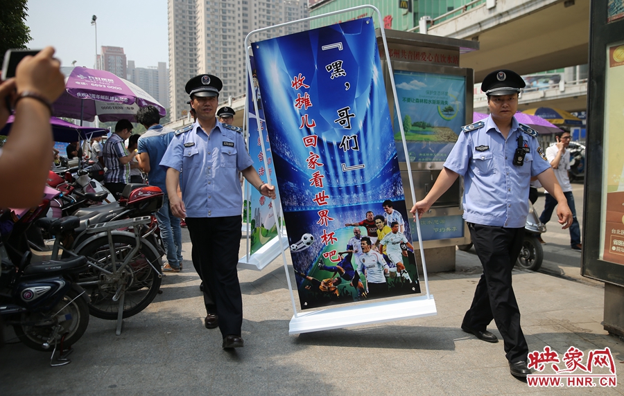 7月2日上午，鄭州市紫荊山地鐵站出入口，執(zhí)法人員抬著寫有勸導(dǎo)語的宣傳板，前往占道經(jīng)營攤位“圍觀執(zhí)法”