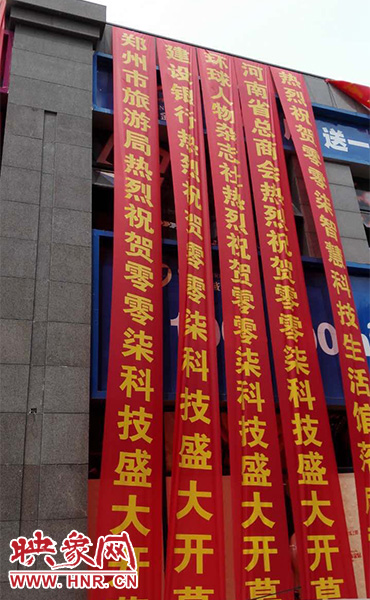 路邊一棟樓上懸掛著二三十條紅色條幅，全部是祝賀一家公司開(kāi)業(yè)的。