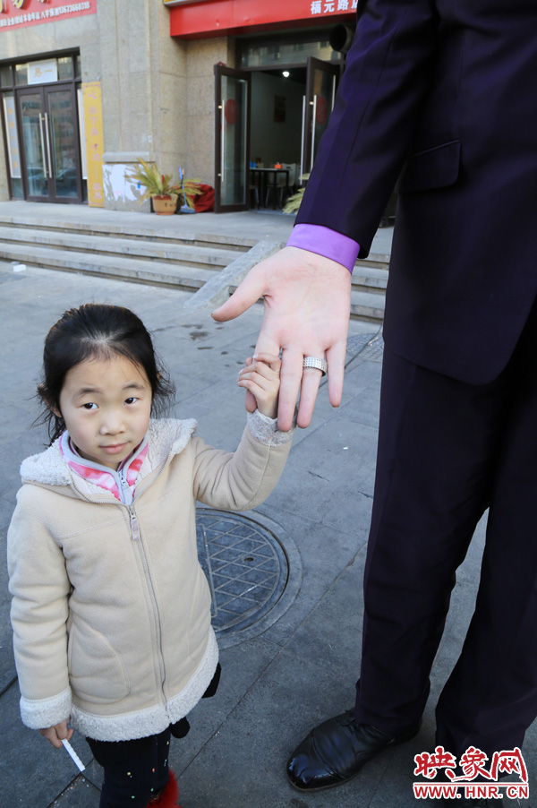 巨人“張歡”牽著一名漂亮的小女孩，兩人的手大小對比非常明顯。