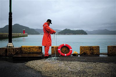 7月6日，韓國珍島，一名海岸警察在港口系救生圈。4月，客輪在珍島近海發(fā)生沉船事故后，仍有11人下落不明。