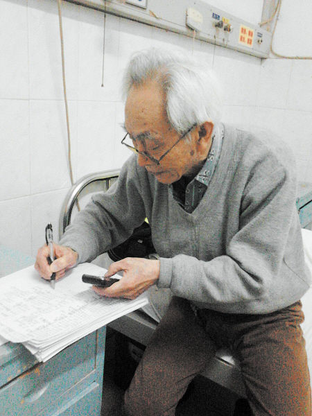 杜修源老人埋頭寫著特殊的“日記”。 李卓 攝