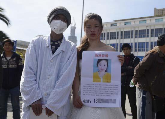 昆明火車站廣場(chǎng)上，24歲的黃習(xí)菊身穿潔白的婚紗，帶著身患白血病的弟弟征婚。