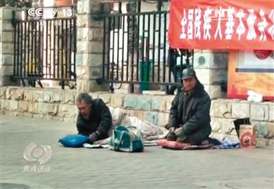 工人體育場(chǎng)北路，兩位乞討者路邊乞討，并輪流扮成“病人”（躺地者）。 央視截圖
